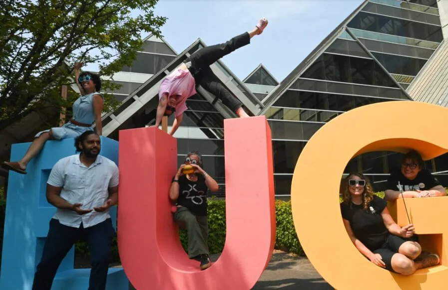 People posing on top of giant letters that spell out "BUG".